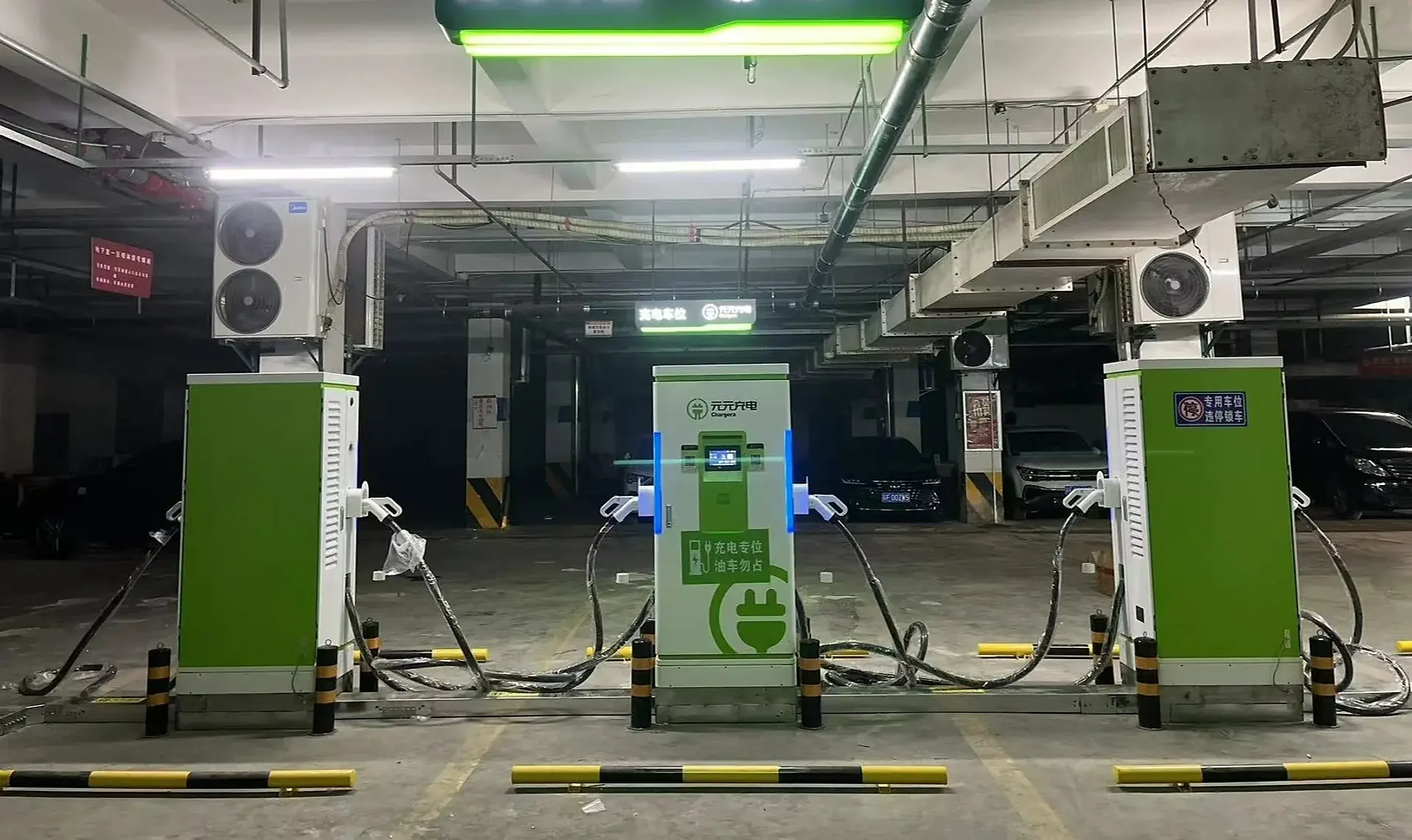 Três carregadores rápidos verdes e brancos em uma garagem subterrânea