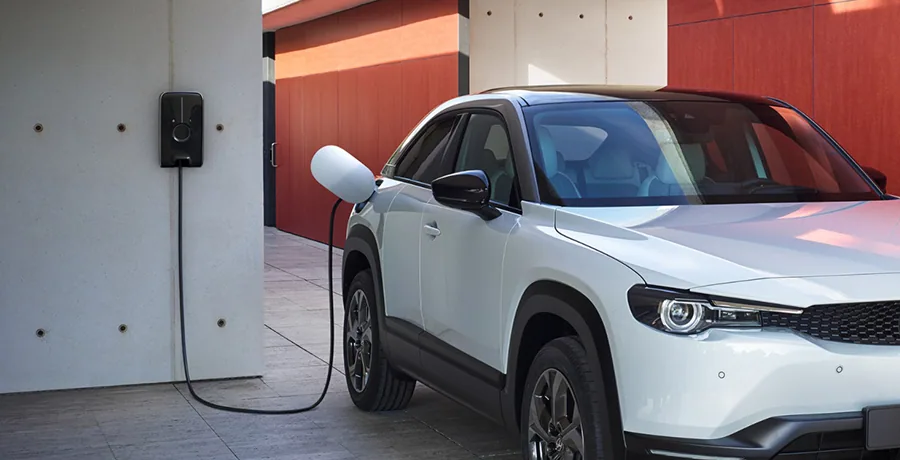 Carregador de parede instalado na garagem de uma casa, com carro elétrico conectado