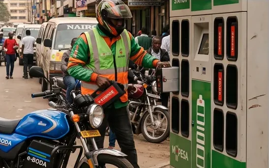 Motociclista retirando uma bateria carregada de um gabinete de troca de baterias em uma rua movimentada