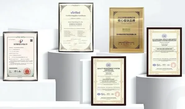Certificados emoldurados e uma placa dourada, expostos sobre pedestais brancos